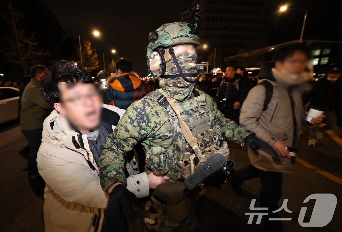 윤석열 대통령이 비상계엄령을 전격 선포한 가운데 4일 새벽 서울 여의도 국회 앞에서 시민들이 경내로 진입하려는 계엄군을 붙잡아 막아서고 있다. 2024.12.4/뉴스1 ⓒ News1 구윤성 기자