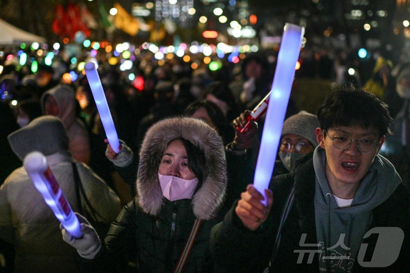  2024년 12월 7일 밤 서울 국회 밖에서 윤석열 대통령의 탄핵을 주장하는 시위대가 형광봉을 들고 있다. ⓒ AFP=뉴스1