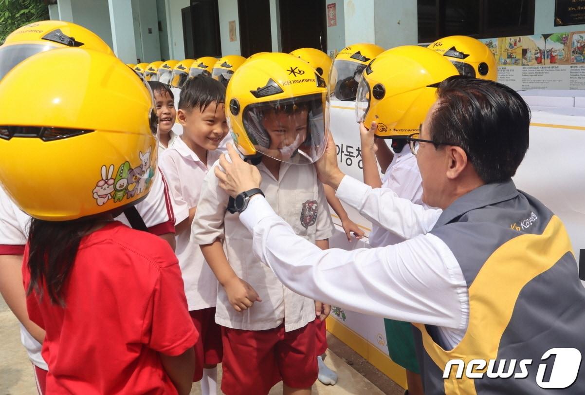 안전모 전달식에 참여한 KB손해보험 조정래 인니법인장이 Sinar Cahaya Kasih 학교 학생들에게 안전모를 씌워주고 있다/사진제공=KB손해보험