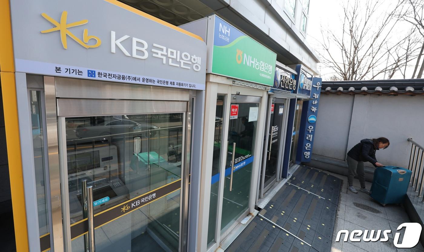 13일 서울 시내에 설치된 시중은행 ATM 기기 앞을 한 시민이 지나고 있다. 2024.3.13/뉴스1 ⓒ News1 신웅수 기자