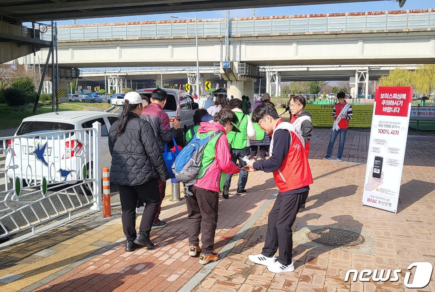 부산은행 직원들이 보이스피싱 수법과 대응 방법을 담은 전단지와 보이스피싱 신고 전화번호가 적힌 볼펜을 배포하고 있다.&#40;BNK부산은행 제공&#41;