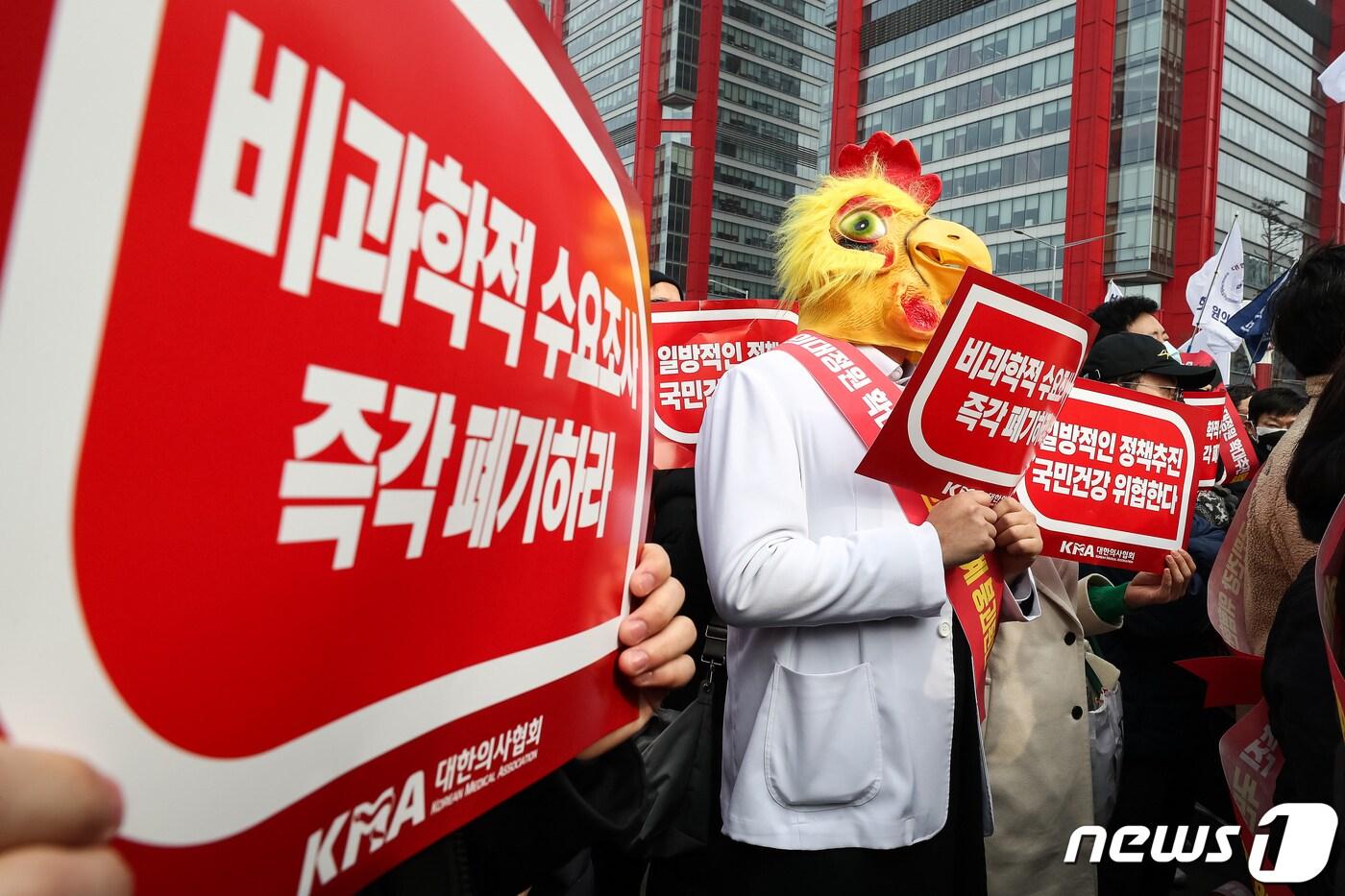 지난 3일 서울 영등포구 여의대로에서 열린 &#39;의대정원 증원 및 필수의료 패키지 저지를 위한 전국 의사 총궐기 대회&#39;에서 한 의사 가운을 입은 참석자가 닭의 탈을 쓰고 손팻말을 들고 있다.  2024.3.3/뉴스1 ⓒ News1 유승관 기자