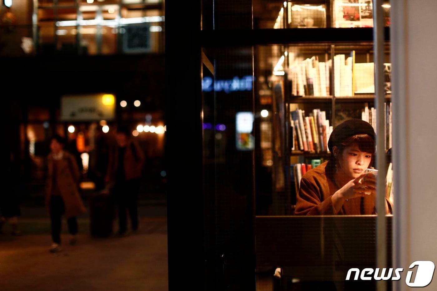 일본 도쿄 메구로구의 한 서점에서 한 여성이 앉아 스마트폰을 확인하고 있다. 2017.03.08/ ⓒ AFP=뉴스1 ⓒ News1 권진영 기자