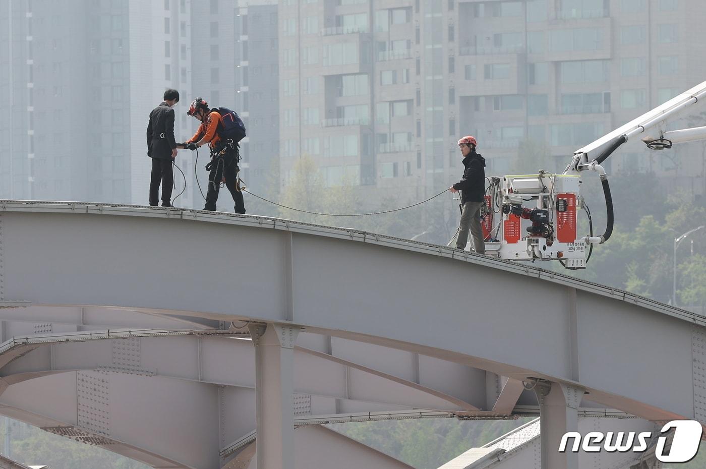 17일 오전 서울 한강대교 노량진 방면에서 교량 위에 올라가 소동을 벌이고 있는 신원을 알 수 없는 남성을 현장에 출동한 소방대원들이 설득해 내려올 준비를 하고 있다. 2024.4.17/뉴스1 ⓒ News1 김도우 기자