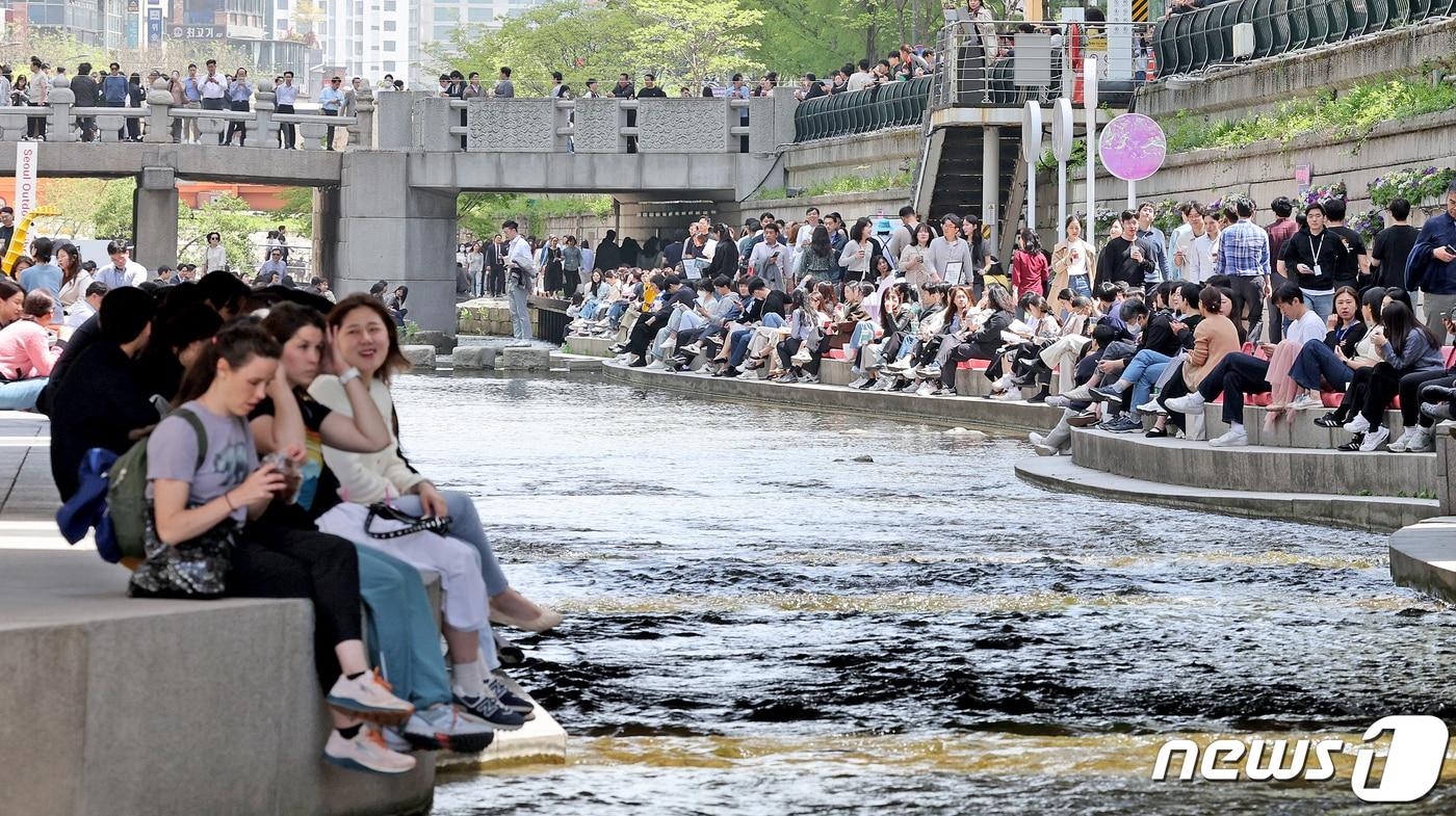 서울지역 낮 최고기온이 25도까지 오르며 초여름 날씨를 보인 18일 오후 서울 중구 청계천을 찾은 시민과 관광객이 물가에 앉아 더위를 식히고 있다. 2024.4.18/뉴스1 ⓒ News1 장수영 기자