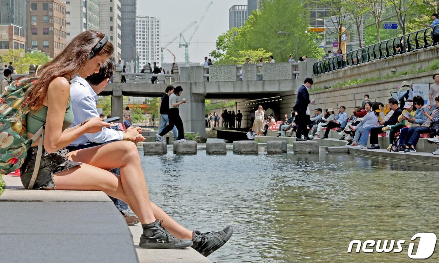 서울지역 낮 최고기온이 25도까지 오르며 초여름 날씨를 보인 18일 오후 서울 중구 청계천을 찾은 관광객이 물가에 앉아 더위를 식히고 있다. 2024.4.18/뉴스1 ⓒ News1 장수영 기자