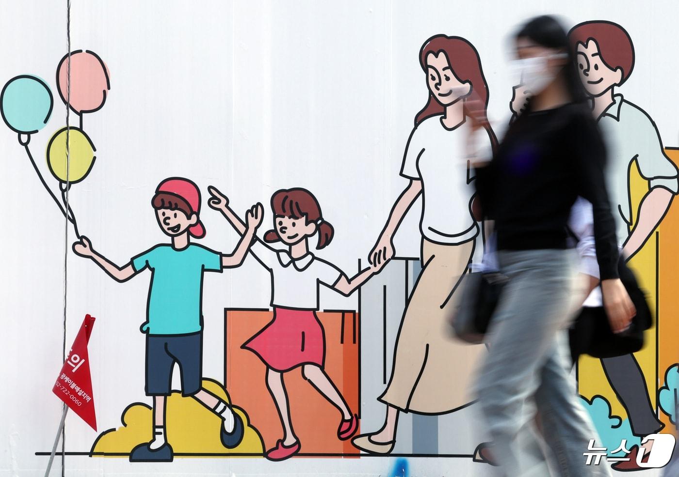 서울 도심의 공사장 가림막에 그려진 행복한 가족 그림 앞으로 시민이 지나고 있다. 2024.4.24/뉴스1 ⓒ News1 박정호 기자