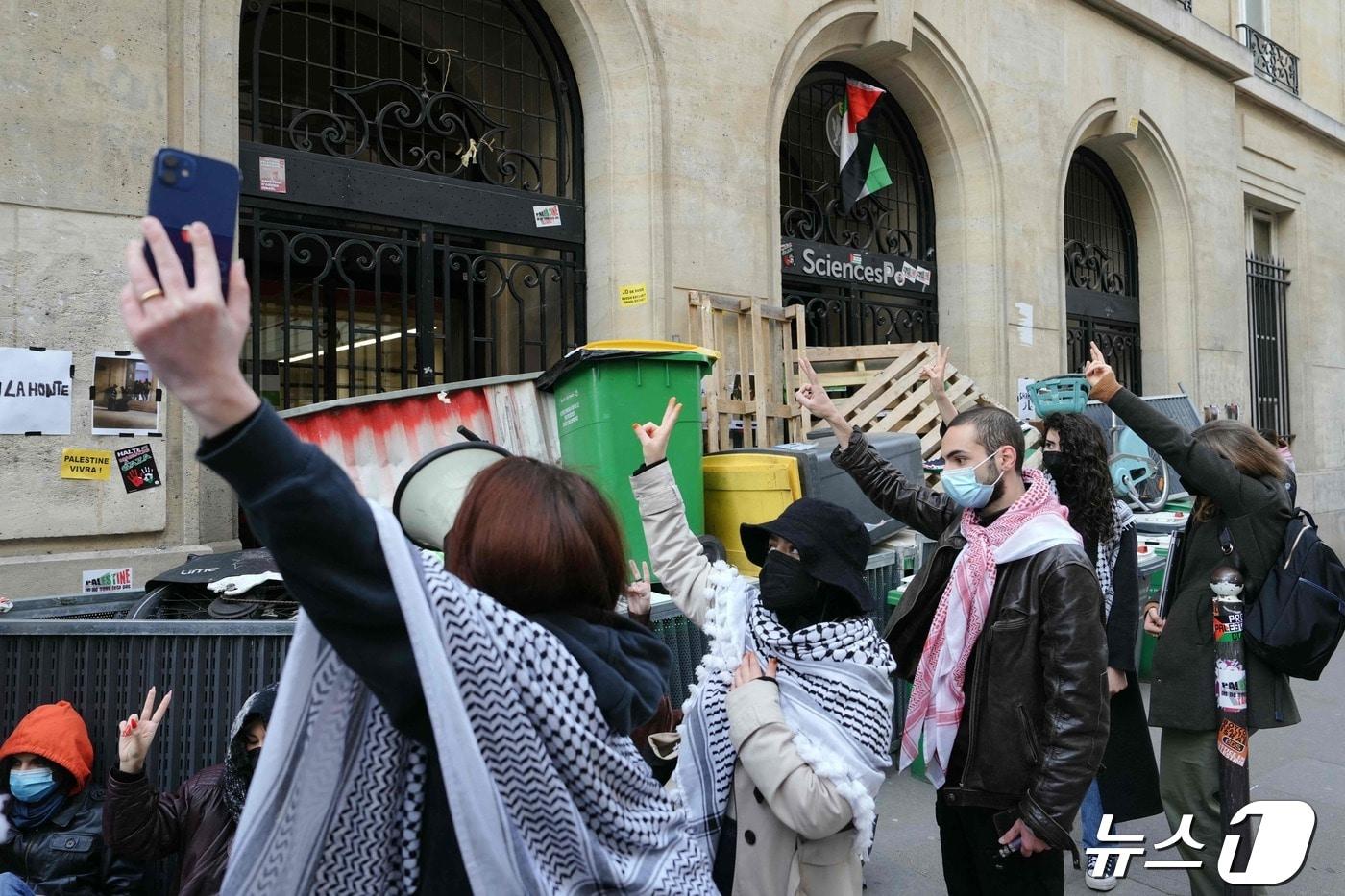 친팔레스타인 시위대가 26일 프랑스 최고 명문 시앙스포 파리&#40;Sciences Po Paris· the Institute of Political Studies&#41; 학교 건물을 점거한 채 출입구를 바리케이드로 막고 있는 동료들에게 승리의 V자를 표하고 있다. ⓒ AFP=뉴스1 ⓒ News1 정지윤기자