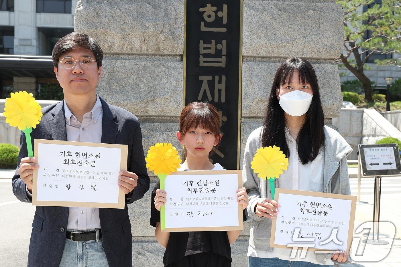 서울 종로구 헌법재판소 앞에서 기후 헌법소원의 마지막 공개변론을 앞두고 열린 환경단체 기자회견에서 시민기후소송 청구인인 황인철 씨&#40;왼쪽부터&#41;, 청소년기후소송 청구인 김서경 씨, 아기기후소송 청구인 한제아 양이 최후진술문을 들고 있다. 2024.5.21/뉴스1 ⓒ News1 신웅수 기자