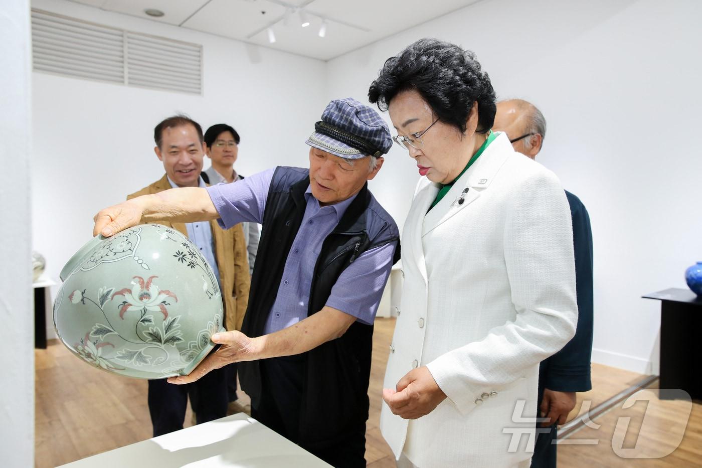 김경희 시장&#40;흰색 상의&#41;이 광화문역 172G 갤러리에서 열리고 있는 ‘이천시 도자 명장 20인 작품전’에서 한 명장으로부터 작품에 대한 설명을 듣고 있다.&#40;이천시 제공&#41;