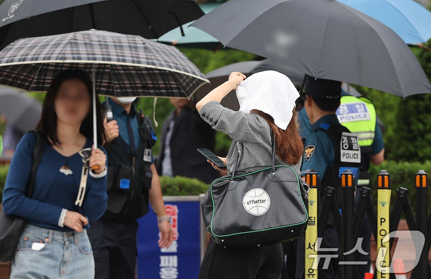 수도권 지역에 비가 내리는 26일 오후 서울 용산구 전쟁기념관에서 우산을 챙기지 못한 한 시민이 수건으로 비를 막으며 발걸음을 옮기고 있다. 2024.5.26/뉴스1 ⓒ News1 김진환 기자