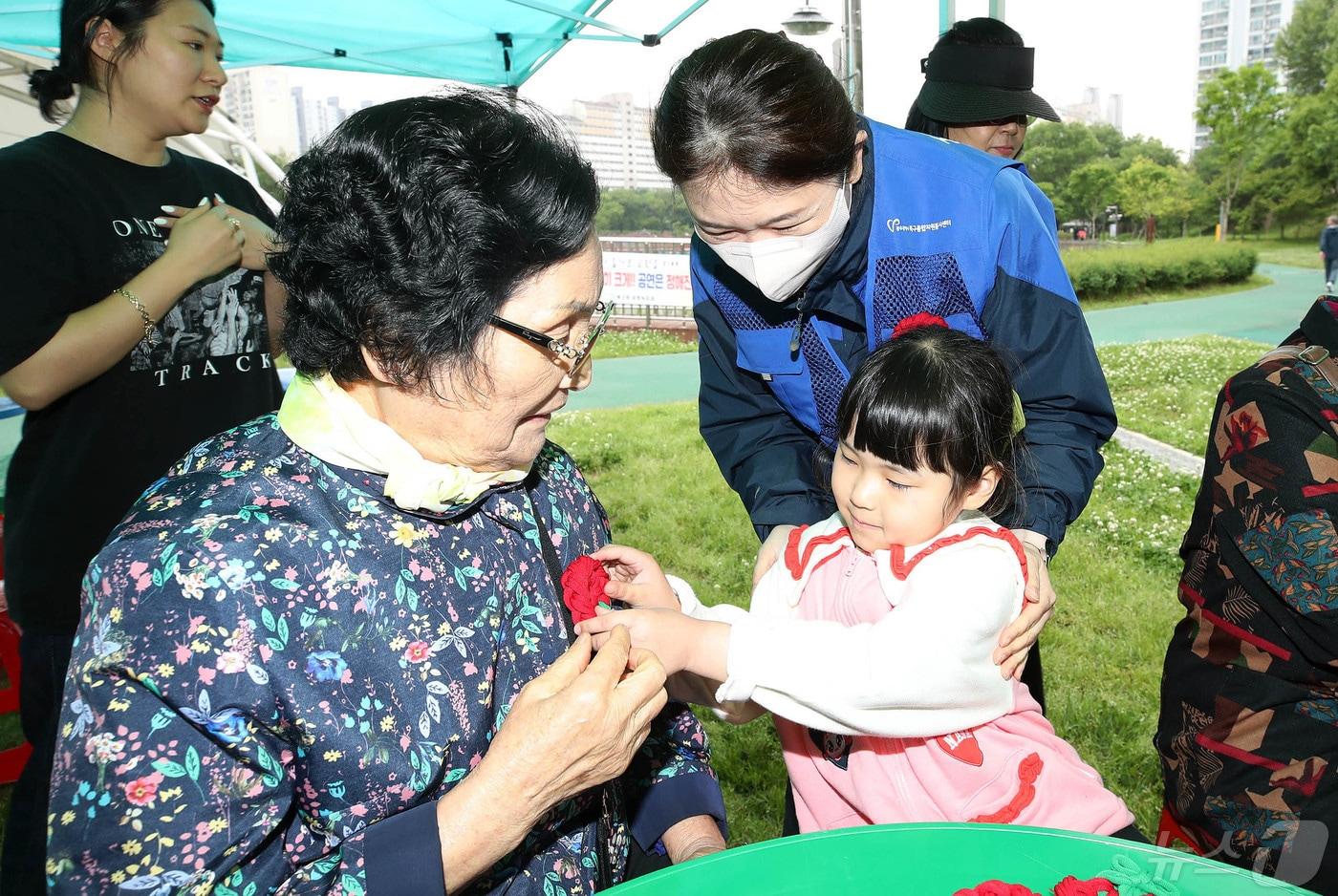 7일 광주 북구 양산호수공원 야외공연장에서 한빛유치원 아이들이 어머니들에게 직접 만든 수제 카네이션을 달아 드리고 있다.&#40;광주 북구 제공&#41;