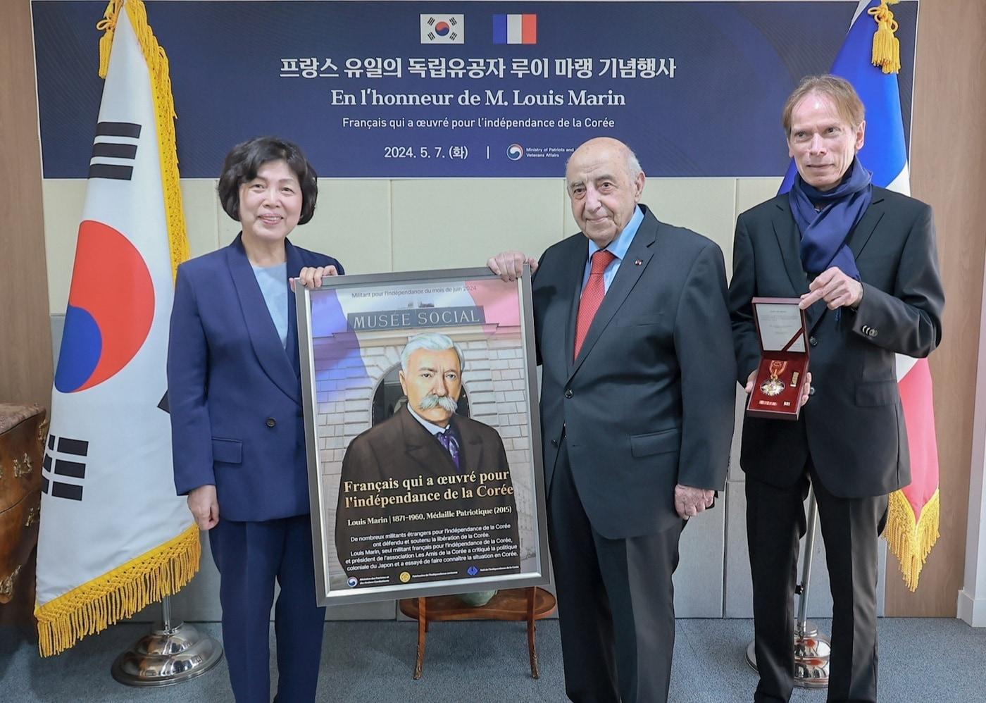 강정애 국가보훈부 장관이 현지시각 7일 오전 프랑스 파리 주프랑스 대사관에서 열린 프랑스인 독립유공자 &#39;루이 마랭&#39; 건국훈장 전수 행사에 참석해 해외과학 아카데미 회장에게 루이 마랭 건국훈장 &#40;2015년 애국장&#41;과 이달의 독립운동가 포스터를 전달하고 있다.&#40;국가보훈부 제공&#41;