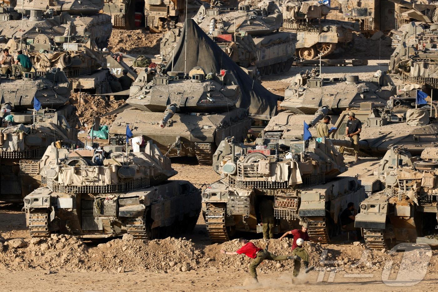 이스라엘과 가자지구의 접경 지역에 이스라엘군의 탱크가 여러 대 놓여있는 가운데 두 이스라엘군 병사가 축구를 하고 있다. 2024.06.03 ⓒ 로이터=뉴스1 ⓒ News1 정지윤 기자