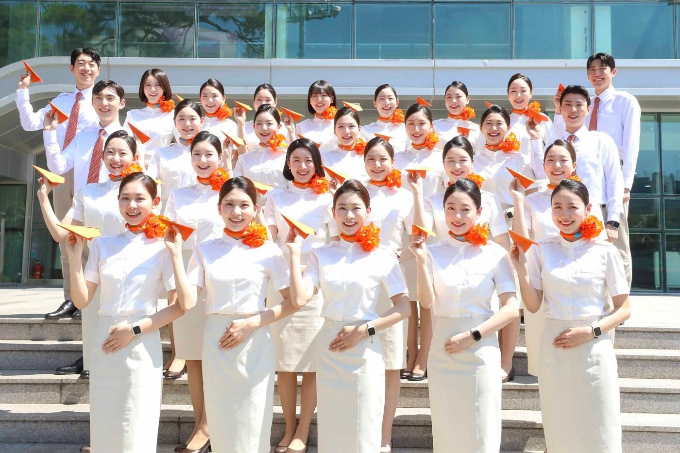 제주항공 취항 18주년을 맞아 제주항공 객실훈련센터 앞에서 교육중인 신입승무원들이 감귤빛 종이비행기를 날리고 있다.&#40;제주항공 제공&#41;