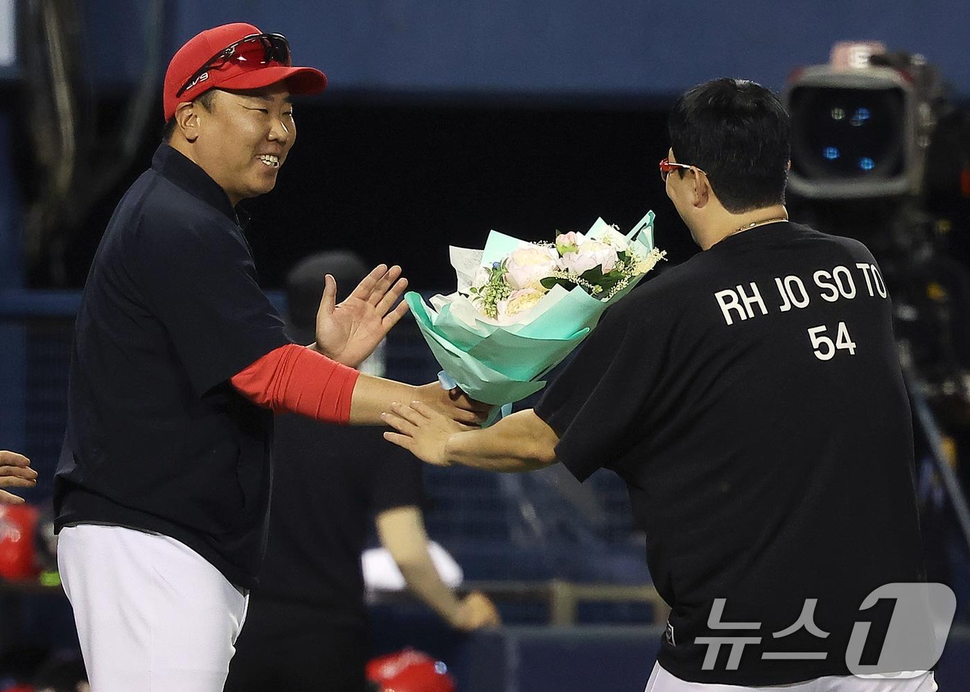 10일 오후 서울 송파구 잠실야구장에서 열린 프로야구 &#39;2024 신한 SOL 뱅크 KBO리그&#39; KIA 타이거즈와 LG 트윈스의 경기, 5대2 승리를 거둔 KIA 이범호 감독이 이날 선발 등판으로 KBO리그 최초로 400경기 등판 신기록과 함께 4회말 선두 타자 오스틴 딘을 투수 직선타로 잡아내 올 시즌 100이닝을 채우면서 역대 3번째로 11시즌 연속 100이닝 기록을 세운 양현종에게 꽃다발을 전달하고 있다. 2024.7.10/뉴스1 ⓒ News1 김진환 기자