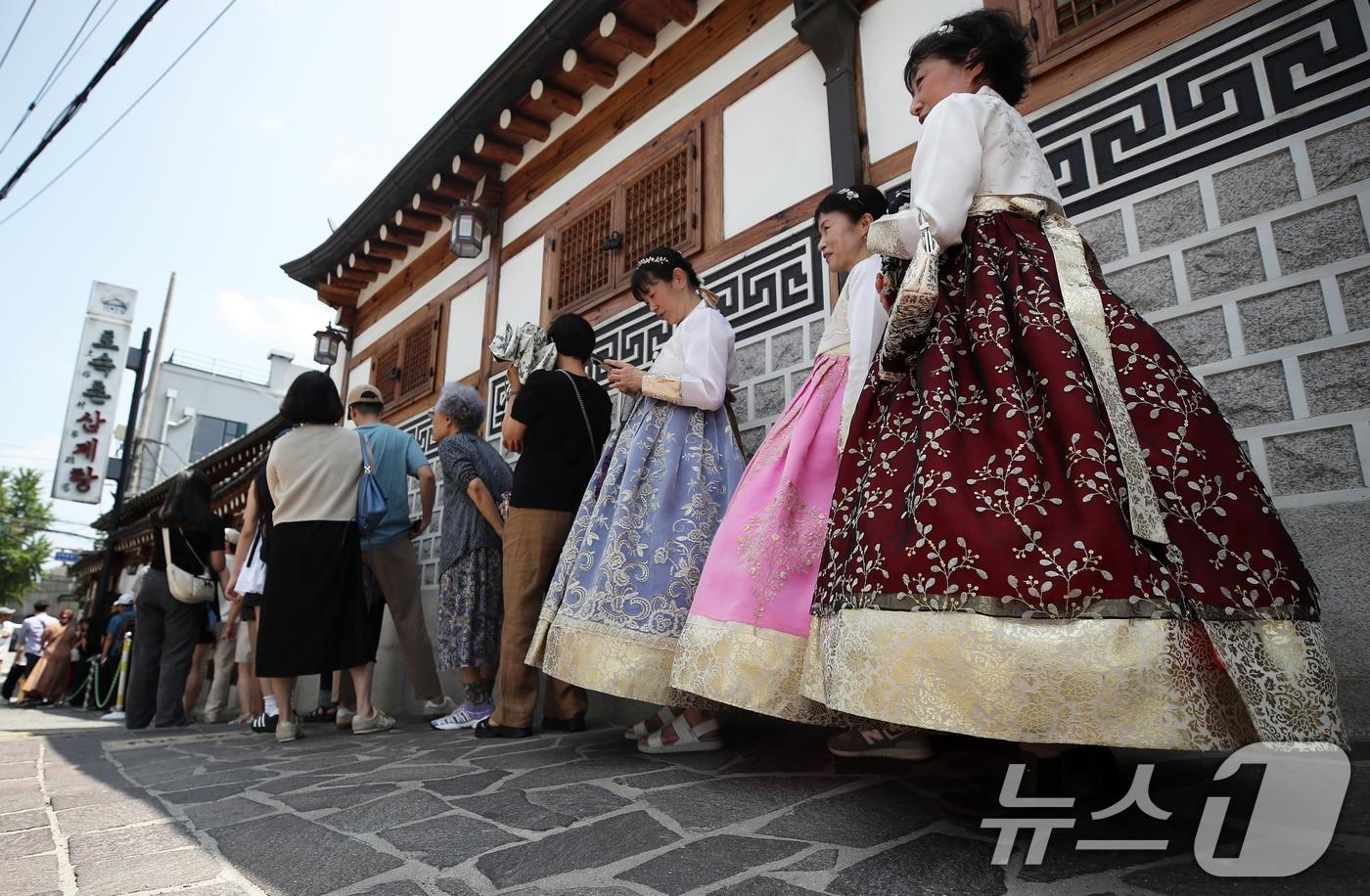 초복을 하루 앞둔 14일 서울 종로구의 한 삼계탕 전문점을 찾은 시민과 외국인 관광객들이 길게 줄을 지어 입장 순서를 기다리고 있다. 2024.7.14/뉴스1 ⓒ News1 오대일 기자