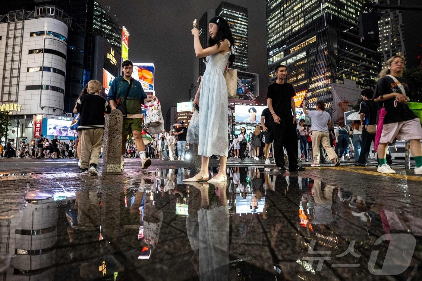 한 여성이 16일 폭우가 그친 도쿄 시부야 지역에서 셀카를 찍고 있다. 2024.07.16 ⓒ AFP=뉴스1 ⓒ News1 장시온기자