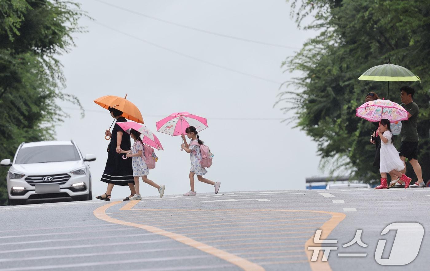 비가 내리는 19일 오전 광주 광산구 신창지구에서 학생들이 부모의 손을 잡고 등굣길 발걸음을 재촉하고 있다. 2024.7.19/뉴스1 ⓒ News1 김태성 기자