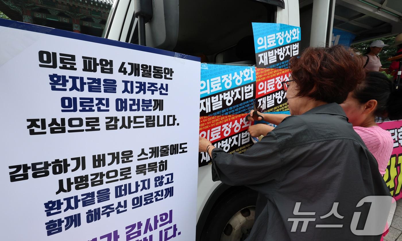 한국유방암환우총연합회·한국환자단체연합회·한국희귀난치성질환연합회 등 총 92개 환자단체 회원들이 4일 오전 서울 종로구 보신각 앞에서 열린 &#39;의사 집단휴진 철회 및 재발방지법 제정 환자촉구대회&#39;를 앞두고 피켓을 부착하고 있다. 2024.7.4/뉴스1 ⓒ News1 김진환 기자