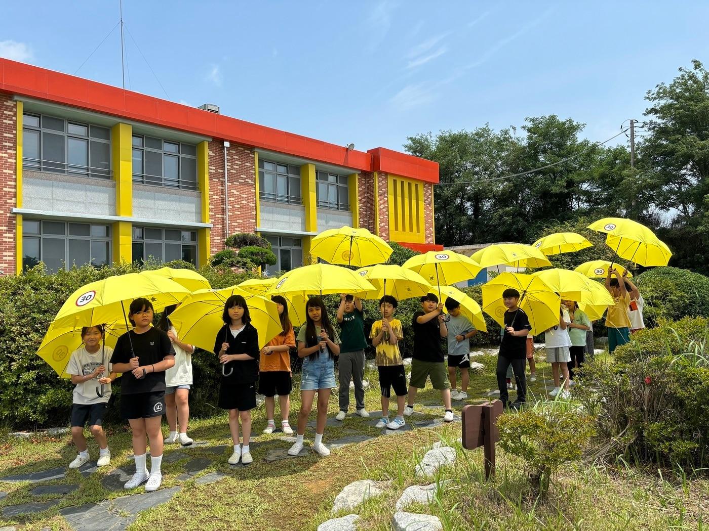 LG헬로비전은 지난 3일 전북 부안남초등학교에서 ‘어린이가 만드는 기후동행학교’ 프로그램을 진행했다. 사진은 학생들이 플라스틱으로 만들어진 안전우산을 들고 있는 모습. &#40;LG헬로비전 제공&#41;