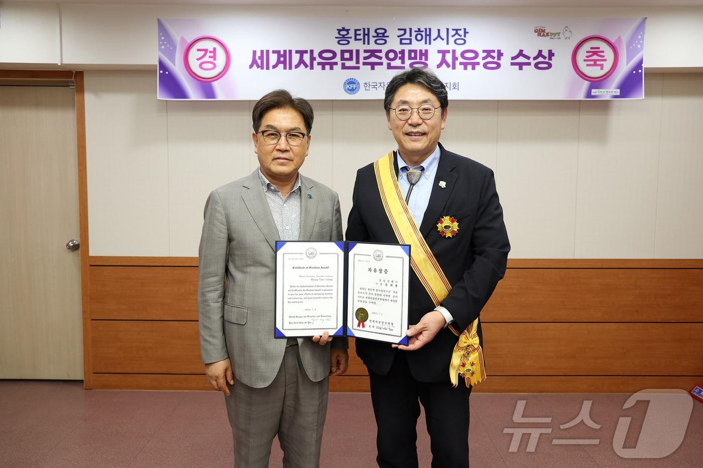 홍태용 김해시장&#40;오른쪽&#41;이 9일 시청에서 김용수 한국자유총연맹 경남지부 회장으로부터 자유장을 전수받고 있다.