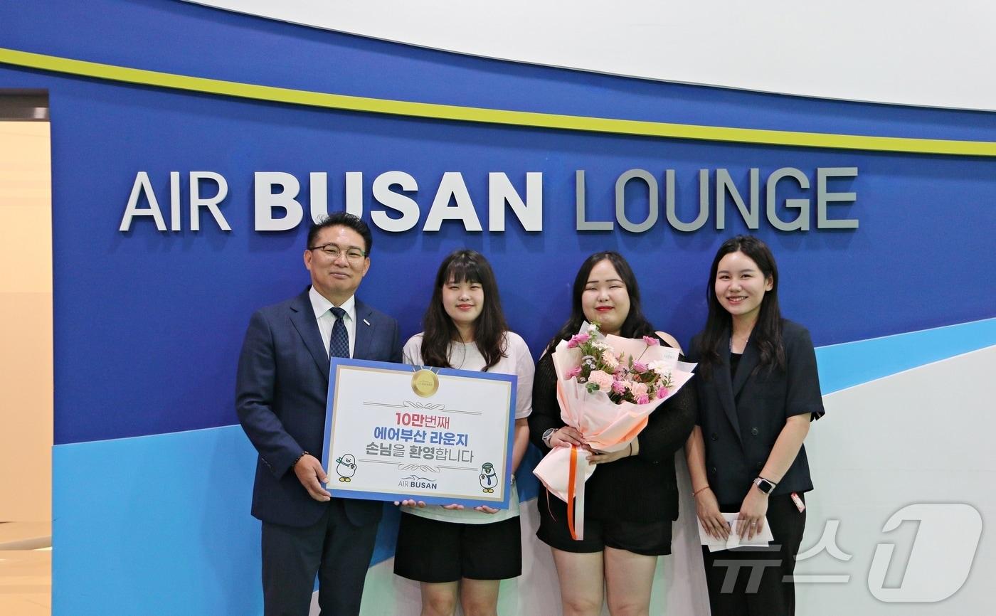 1일 김해공항 에어부산 라운지에서 마호진 에어부산 영업본부장&#40;맨 왼쪽&#41;과 관계자가 10만 번째 입장객에게 국제선 왕복항공권과 기념품을 전달한 후 기념 촬영을 하고 있다.&#40;에어부산 제공&#41;