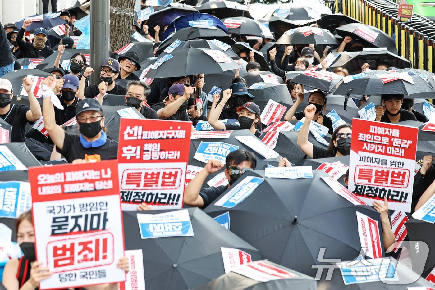 &#39;티메프 사태&#39; 피해자들이 지난 18일 오후 서울 종로구 사직로 일대에서 열린 검은우산 집회에서 구호를 외치고 있다. 이날 참가자들은 정부에 실효성 있는 구제방안 마련과 특별법 제정을 촉구했다.ⓒ News1 민경석 기자