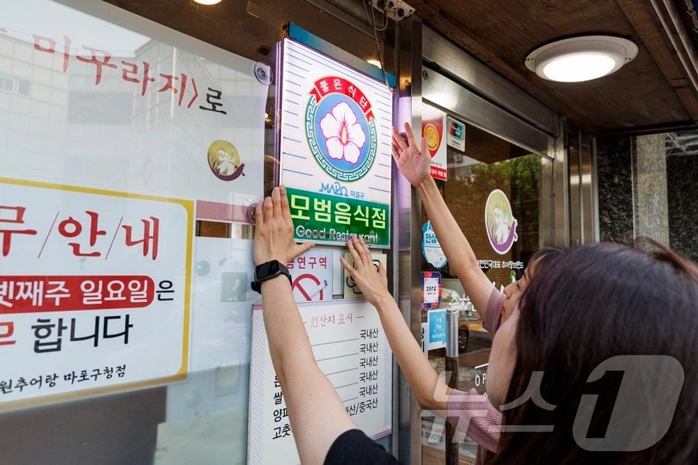 마포구 직원이 모범음식점으로 지정된 관내 음식점에 표지판을 설치하고 있다.&#40;마포구청 제공&#41;