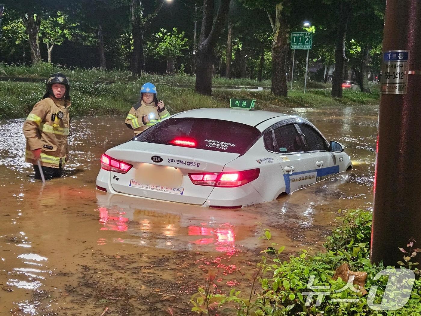 21일 오전 충북 청주시 석소동에서 집중호우로 인해 도로가 침수되어 출동한 소방대원들이 고립된 택시차량을 이동 조치하고 있다. &#40;소방청 제공&#41; 2024.9.21/뉴스1