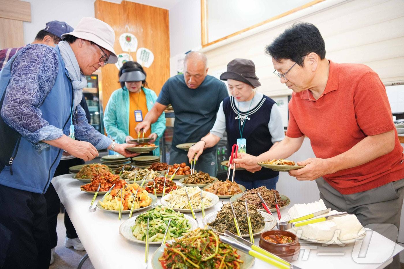 강기정 광주시장이 27일 북구 무등산 평촌마을 무돌길 쉼터에서 환경부 선정 체류형 생태관광 체험단과 함께 음식을 그릇에 담고 있다.&#40;광주시 제공&#41;2024.9.27/뉴스1 