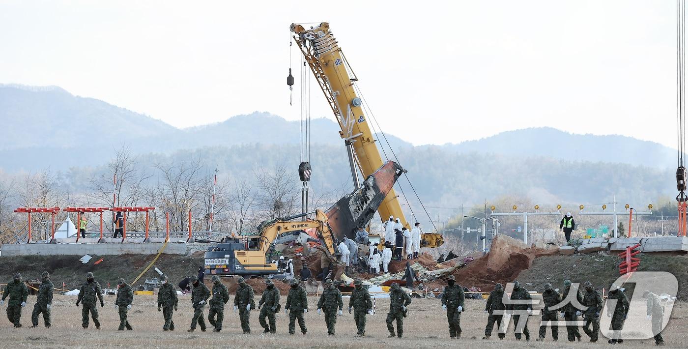 제주항공 여객기 참사 7일째인 4일 오후 전남 무안국제공항 참사 현장에서 특전사 대원들의 수색 작업 뒤로 방위각시설&#40;로컬라이저&#41;에서 엔진 인양 작업이 진행되고있다. 2025.1.4/뉴스1 ⓒ News1 김진환 기자