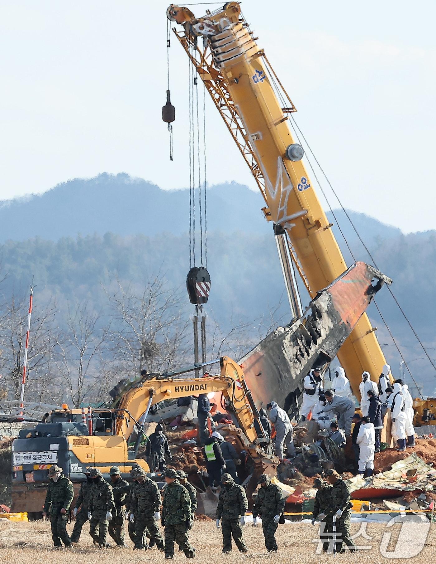 제주항공 여객기 참사 7일째인 4일 오후 전남 무안국제공항 참사 현장에서 수색 작업을 하는 특전사 대원들의 뒤로 방위각시설&#40;로컬라이저&#41;에서 엔진 인양 작업이 진행되고 있다. 2025.1.4/뉴스1 ⓒ News1 김진환 기자