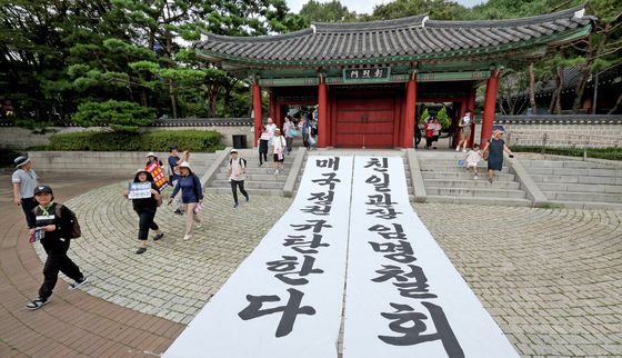 정권 규탄 대형 현수막 앞 행진하는 시민단체 관계자들