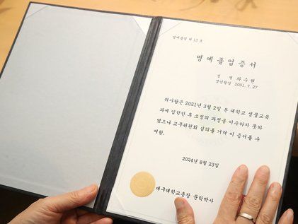 딸의 명예학위증 어루만지는 아버지