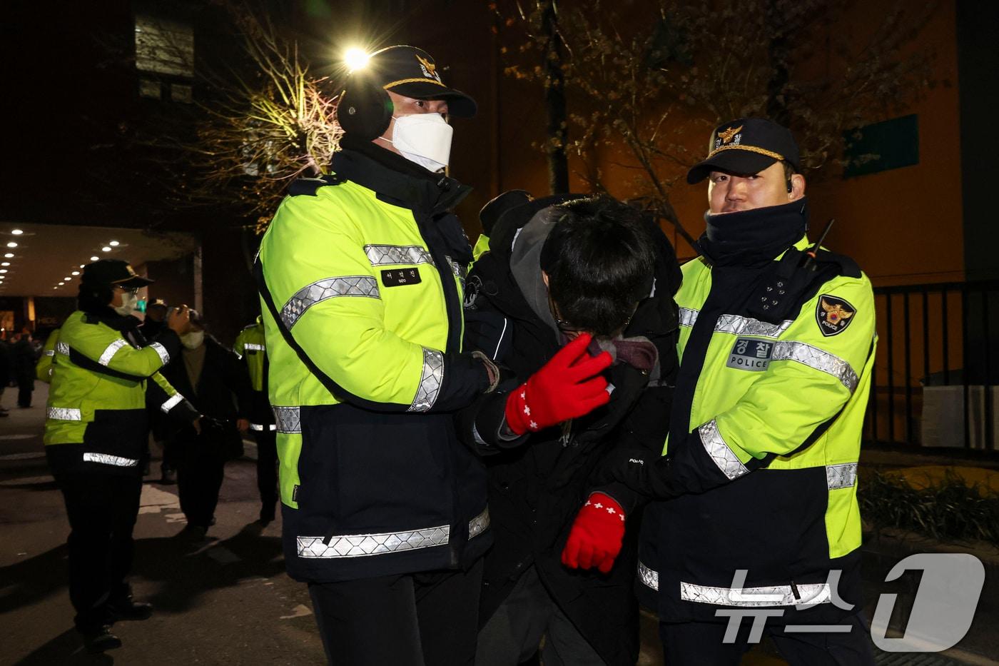 내란 우두머리 혐의로 체포된 윤석열 대통령의 영장실질심사가 열린 18일 오후 서울 마포구 서울서부지방법원에서 윤 대통령의 석방을 촉구하며 법원 담장을 넘어 들어온 한 청년이 경찰에 붙잡혀 있다.(공동취재) 2025.1.18/뉴스1 ⓒ News1 민경석 기자